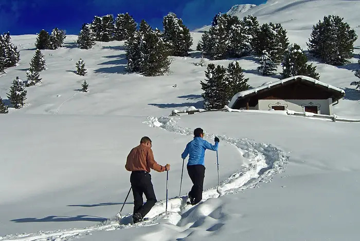Paar bei einer Schneeschuhwanderung zu einer Berghütte